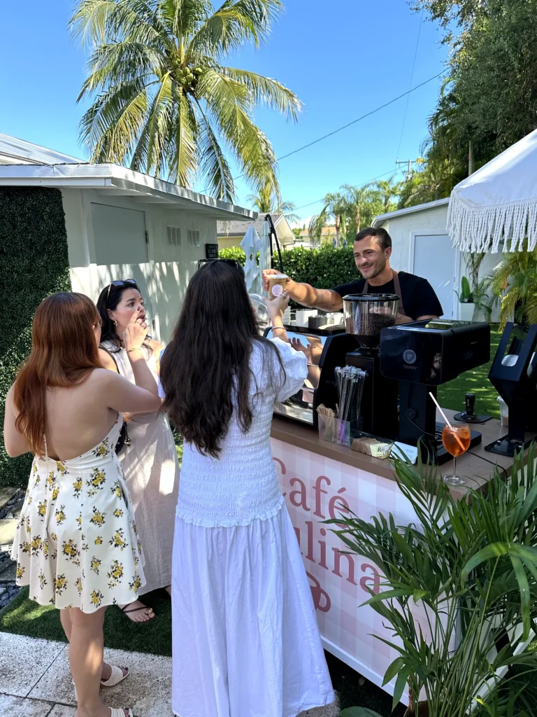 Barista serving iced coffee to guests at a private event with a fully branded coffee cart in pinecrest