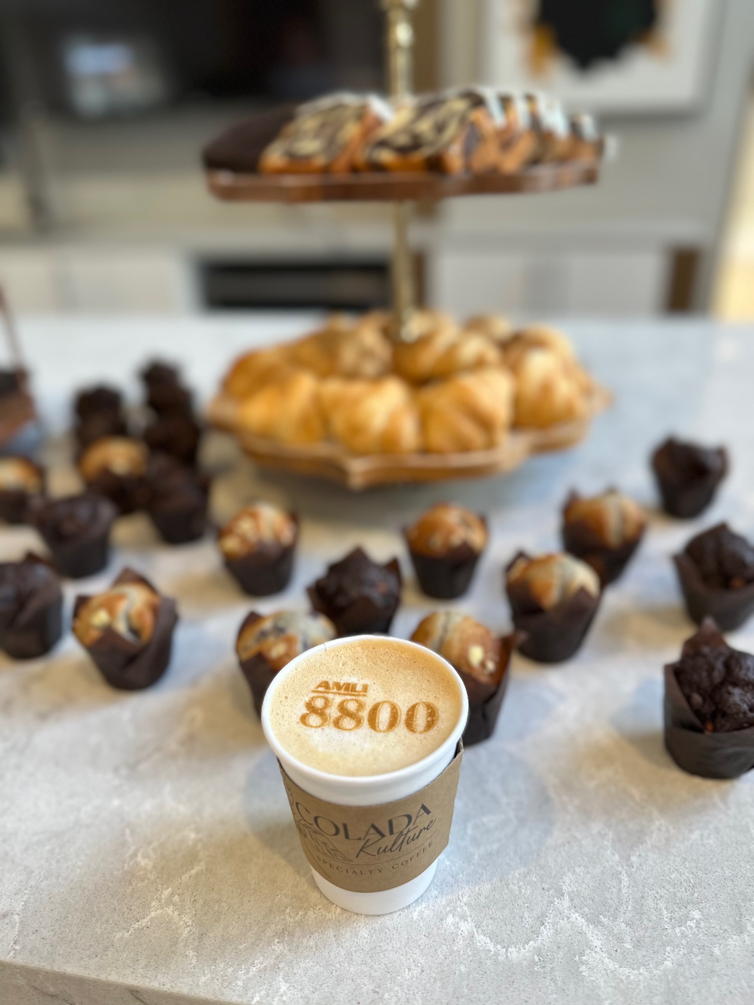Latte with AMLI 8800 logo printed in the foam, served alongside mini pastries at a Doral apartment community coffee event